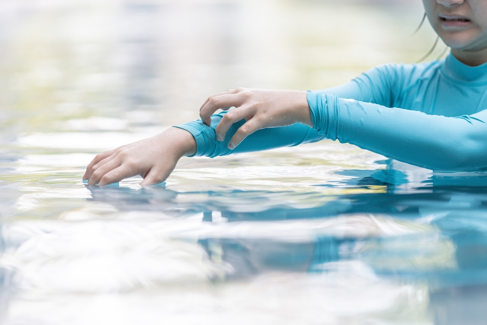 girl itching arm in water