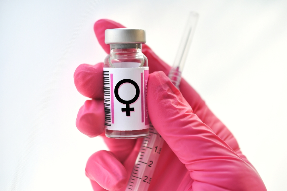 gloved hand holding syringe and vial with female gender symbol